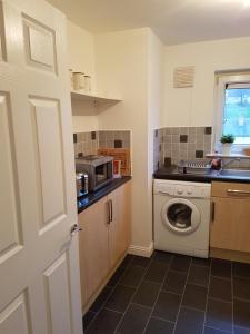 a kitchen with a washing machine and a microwave at Bathgate Contractor and Business Apartment in Bathgate