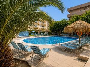 a swimming pool with chairs and umbrellas at Castro Hotel in Amoudara Herakliou