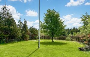 a pole in the middle of a field with a tree at Spætten in Brovst