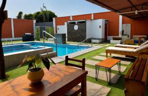 a swimming pool with a wooden table and a table sidx sidx at Búnker de Coco in Pachacamac