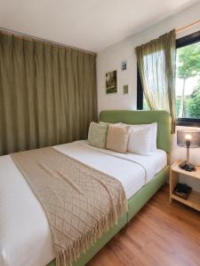 a bedroom with a green bed with a window at How Hide Homestay in Ban Tha Makham
