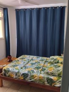 a bed in a room with a blue curtain at Le Courbaril in Le Gosier