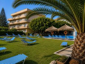 a resort with blue lounge chairs and a palm tree at Castro Hotel in Amoudara Herakliou