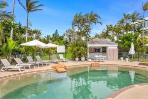 a swimming pool with chairs and umbrellas at a resort at Rosslyn Bay Resort Yeppoon in Yeppoon