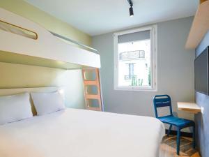 a bedroom with a bed and a chair and a window at ibis budget Saint-Maurice in Saint-Maurice