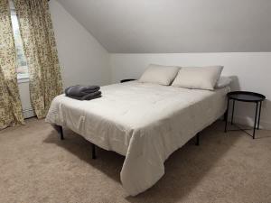 a bedroom with a bed with white sheets and a window at Comfortable 4 Bed Home close to Gillette in Foxborough