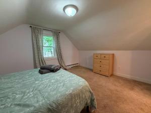a bedroom with a bed and a dresser and a window at Comfortable 4 Bed Home close to Gillette in Foxborough