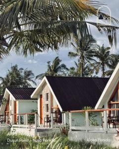 a house with a black roof and palm trees at Aloka Penida in Klungkung