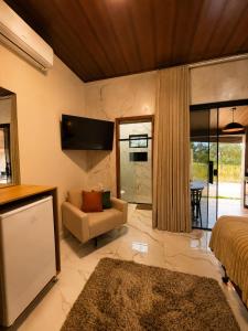 a bedroom with a bed and a couch and a tv at Flats Araras do Vale in Colinas Do Sul