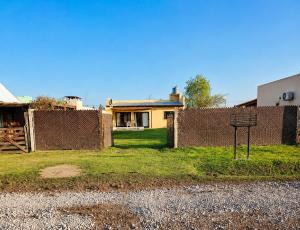 a house behind a fence with a sign in front of it at Rincón Joven II in San Miguel del Monte