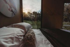 a bedroom with a bed and a window with the sun at Matariki Akura by Tiny Away in Masterton