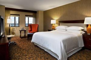 a bedroom with a large white bed and a red chair at Sheraton Springfield Monarch Place Hotel in Springfield
