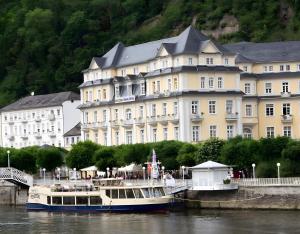 a large building next to a river with a boat at Whirlpool Sauna Pool Bad Ems in Bad Ems