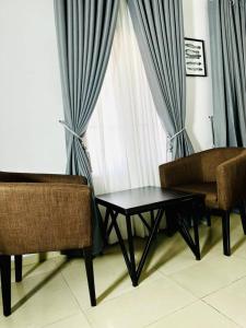 a living room with two chairs and a table and a window at ModexD'Crib in Lagos