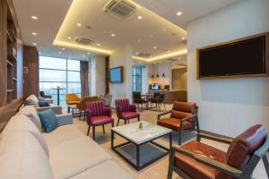 a living room with a couch and chairs and a tv at Sheraton Novi Sad in Novi Sad