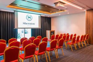 a conference room with red chairs and a screen at Sheraton Novi Sad in Novi Sad