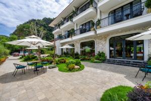 an outdoor patio with tables and umbrellas in front of a building at Heritage Charm Hotel Trang An in Ninh Binh