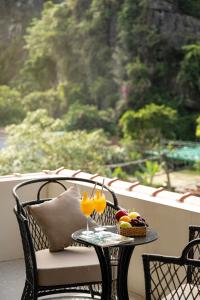 a table with a basket of fruit on a balcony at Heritage Charm Hotel Trang An in Ninh Binh