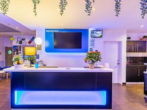 an office with a reception counter with a tv on the wall at Hotel ibis Budget Porto Gaia in Vila Nova de Gaia