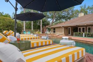 a row of yellow and white chairs with umbrellas by a pool at SolMaré - 5BR, Pool, Spa, Mini-Golf, Outdoor Kitchen, Fire Pit, Game Room in Bradenton