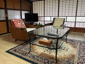 a living room with two chairs and a glass table at 一棟貸ひなたぼっこくらなみ in Nagano