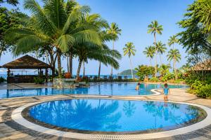 a swimming pool at a resort with palm trees at Frangipani Langkawi Resort in Pantai Cenang