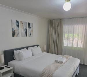 a bedroom with a large white bed and a window at Flaxton Country Lodge in Flaxton