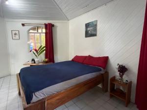 a bedroom with a bed with red pillows and a window at Cozy cabin by the sea in Cahuita