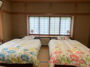 two beds in a room with a window at 民泊ひなたぼっこ1日1組限定離れ貸切 in Nagano