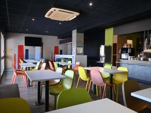 a restaurant with tables and chairs and a kitchen at Hotel ibis Budget Laval in Bonchamp-lès-Laval