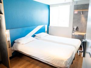 two beds in a room with a blue wall at ibis budget Aix en Provence in Aix-en-Provence