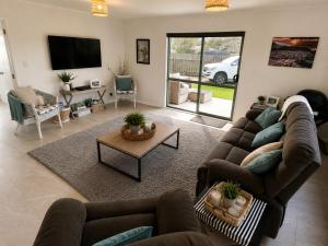 a living room with couches and a table and a tv at Hosts on the Coast Make Memories on Cook in Whitianga