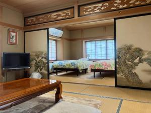 a living room with two beds and a tv at 民泊ひなたぼっこ1日1組限定離れ貸切 in Nagano