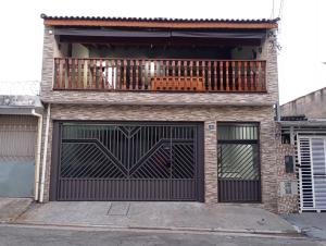 a house with two garage doors and a balcony at Hostel Pouso Gru - Translado Aeroporto Gru grátis in Guarulhos