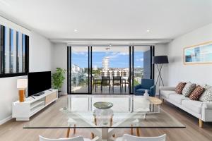 a living room with a white couch and a glass table at Direct Collective - Sea Breeze Mooloolaba in Mooloolaba