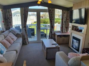 a living room with a couch and a tv at 3-Bed Caravan Sleeps 8 with Enclosed Decking in Fleetwood +6 photos