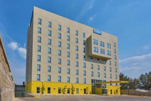 a large white building with a yellow facade at City Express by Marriott Lagos de Moreno in Lagos de Moreno