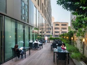 people sitting at tables on a balcony of a building at Mercure Bucharest City Center in Bucharest