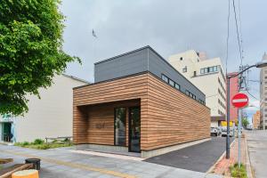 a small building with a wooden facade on a street at Hotel GGG Asahikawa in Asahikawa