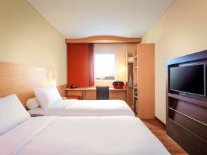 a hotel room with two beds and a flat screen tv at Ibis Makassar City Center in Makassar
