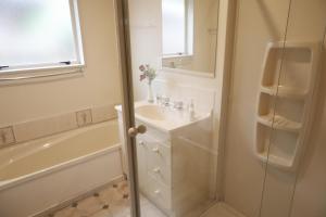 a white bathroom with a sink and a shower at Handy Location, Ocean & Mountain Views, Close to Park - KK96845 in Kaikoura +8 photos