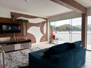 a living room with a blue couch and a large window at Meneghetti Mangaratiba in Mangaratiba
