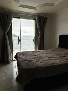 a bedroom with a bed and a large window at Meneghetti Mangaratiba in Mangaratiba