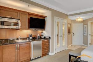 a kitchen with a sink and a tv on the wall at Deluxe Spa 24th floor Signature Studio with Mountain View in Las Vegas +42 photos