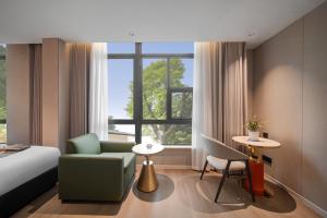 a hotel room with a bed and a chair and a window at Jiting International Hotel Jiaotong University Light Rail Station in Chongqing