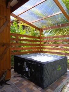a hot tub sitting under a wooden pergola at Gites kaz à klemence - Bungalow karapat - jacuzzi privé et piscine partagée au cœur de la nature à Anse-Bertrand in Anse-Bertrand