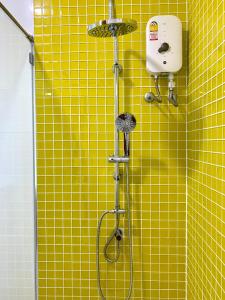 a yellow tiled bathroom with a shower with a shower head at LECAR Home Mustang in Ban Nong Khang
