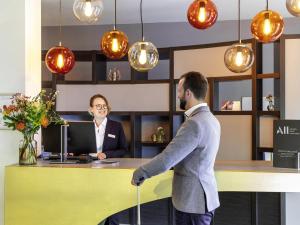 a man with a cane standing in front of a desk at Mercure Hotel Düsseldorf Zentrum in Düsseldorf