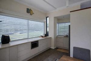 a kitchen with white cabinets and a window with blinds at Fishers Villa - Crescent Head in Crescent Head +14 photos