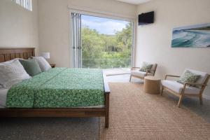 a bedroom with a bed and a large window at Fishers Villa - Crescent Head in Crescent Head